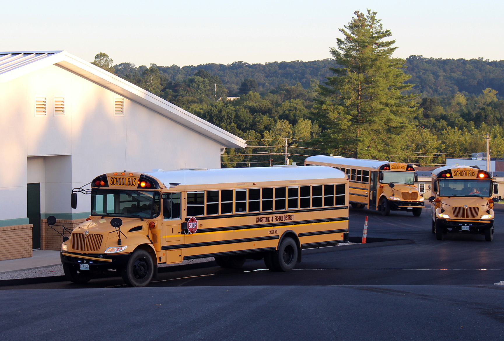 three buses pulling up to a school building - Kingston K-14